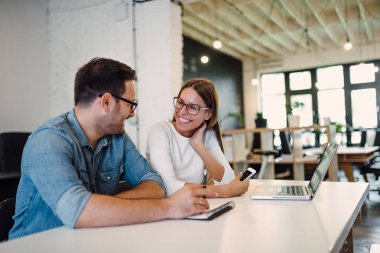 Modern açık alan ofisinde konuşmak iki gülümseyen iş arkadaşları.