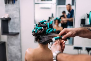 Kuaför saç modeli ile saç curlers bir kadın istemciye yapma.