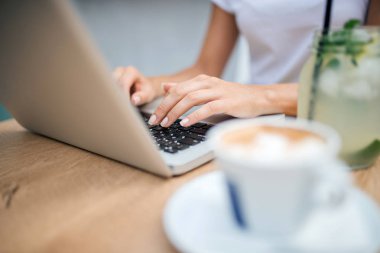 Dizüstü bilgisayar üzerinde kafe kullanarak. Kahve ve limonata masada.