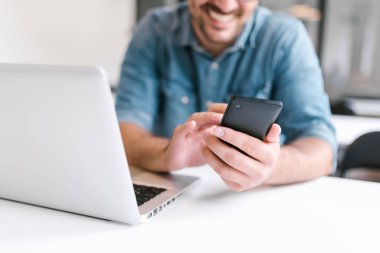 Smartphone ve dizüstü bilgisayar kullanan adam. Yakın çekim.