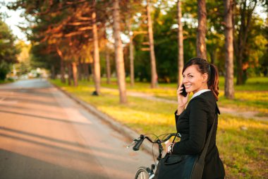Genç kadın bisikletle Smartphone'da konuşuyor. Kopya alanı.