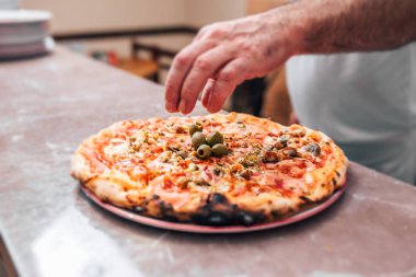 Son dokunuşu ekleme. Zeytin pizza üzerine koyarak Şef. Yakın çekim.