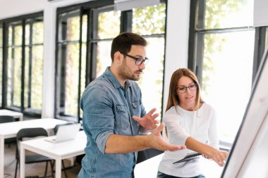 Ekip çalışması kavramı. İki genç insan flipchart önünde tartışıyor.
