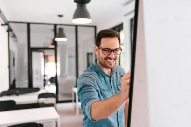 Flipchart üzerinde yazılı gülümseyen genç adam.