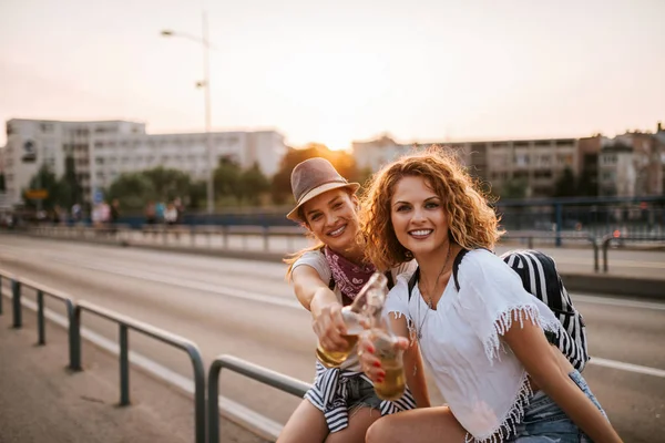 Two girls making a toast at sunset in the city.