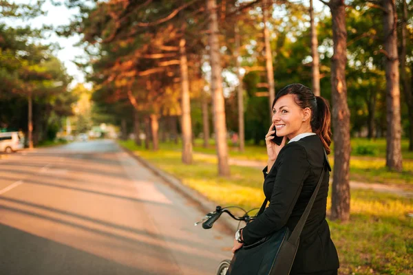 Усміхнена Молода Жінка Розмовляє Телефону Під Час Їзди Велосипеді — стокове фото
