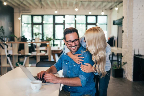 Couple hugging at modern office of a small startup business.