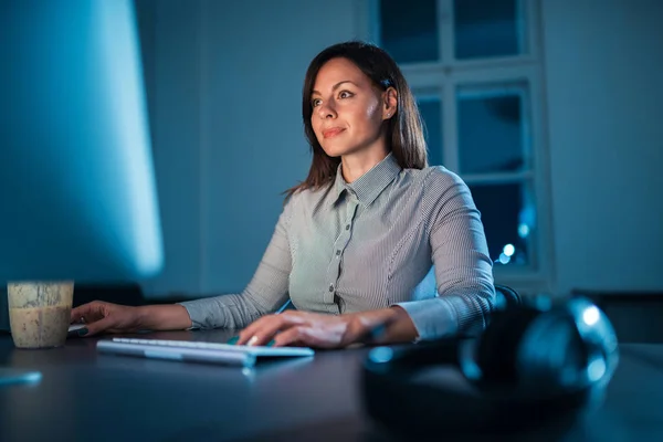 Young businesswoman in office at night working late.