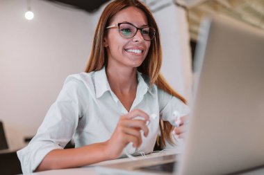 Yakın çekim görüntü gülümseyen genç kadın holding kulaklık ve laptop arıyorum.