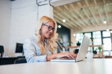 Dizüstü bilgisayarda çalışma kulaklık ile gülümseyen Genç Çevirmen.