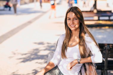 Kameraya bakarak bir bankta oturan bir gülümseyen casual kız açık potrait.