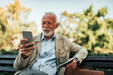 Komuta sizde bankta otururken cep telefonuyla gülümseyen.