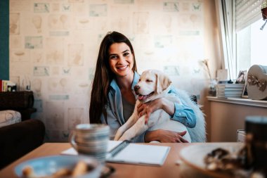 Genç kadın kucaklama sevimli köpek vasıl ev gülümseyen.