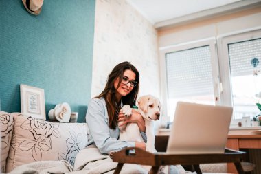 Kız video seslenmek üstünde laptop sahip köpek yavrusu.