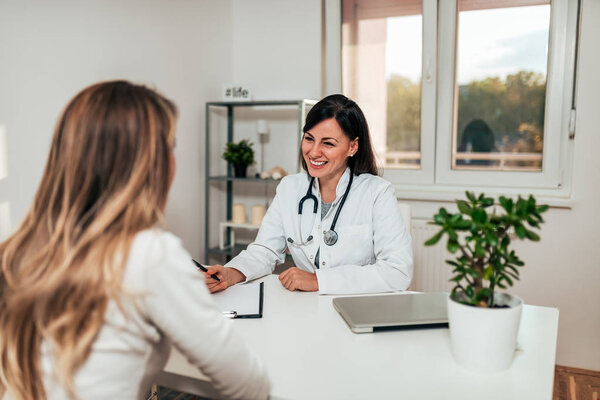 Beautiful young female doctor smiling while talking to her patient.