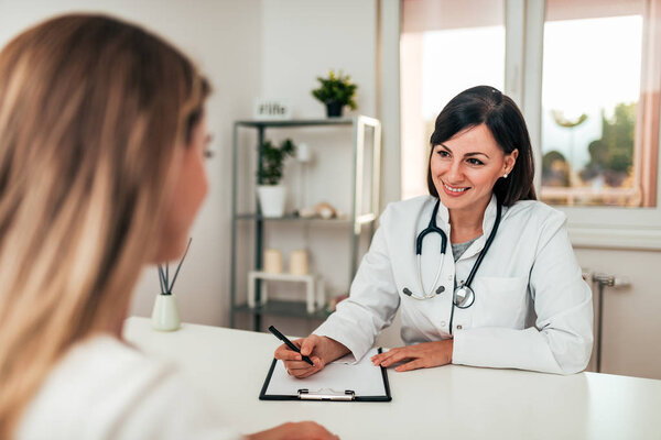 Smiling young female doctor talking to a patient in modern office.