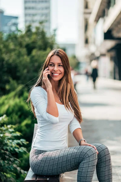 Smiling Young Woman Talking Mobile Phone While Sitting Bench — Stock Photo, Image