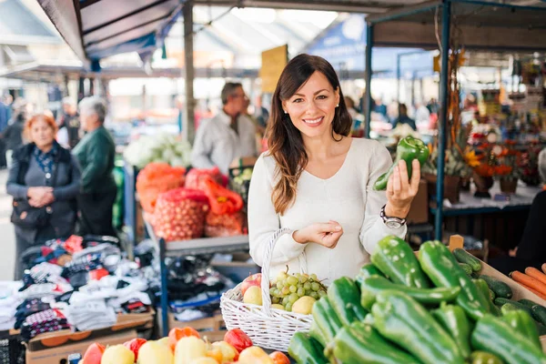 Genç kadın bir yerel gıda pazarında sebze seçme.