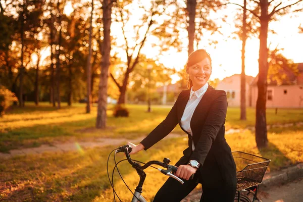 Joven Mujer Sonriente Montando Bicicleta Por Parque Después Del Trabajo —  Fotos de Stock