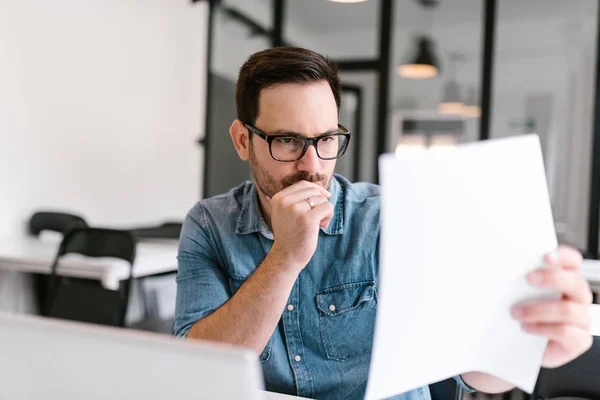 Close-up image of puzzled man looking at documents.