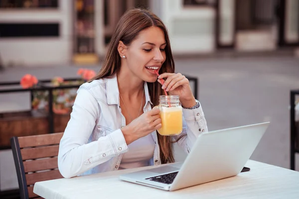 Junge Frau Trinkt Orangensaft Und Schaut Auf Laptop Während Sie — Stockfoto