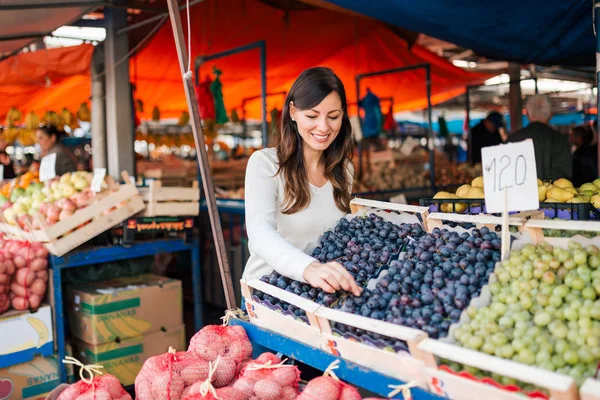 ストリート マーケットで果物を買う若い笑顔の女性 — ストック写真