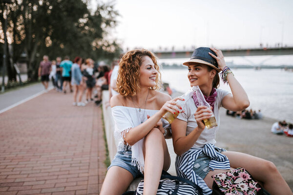 Summertime fun. Girls enjoying drinks near the river in the city.