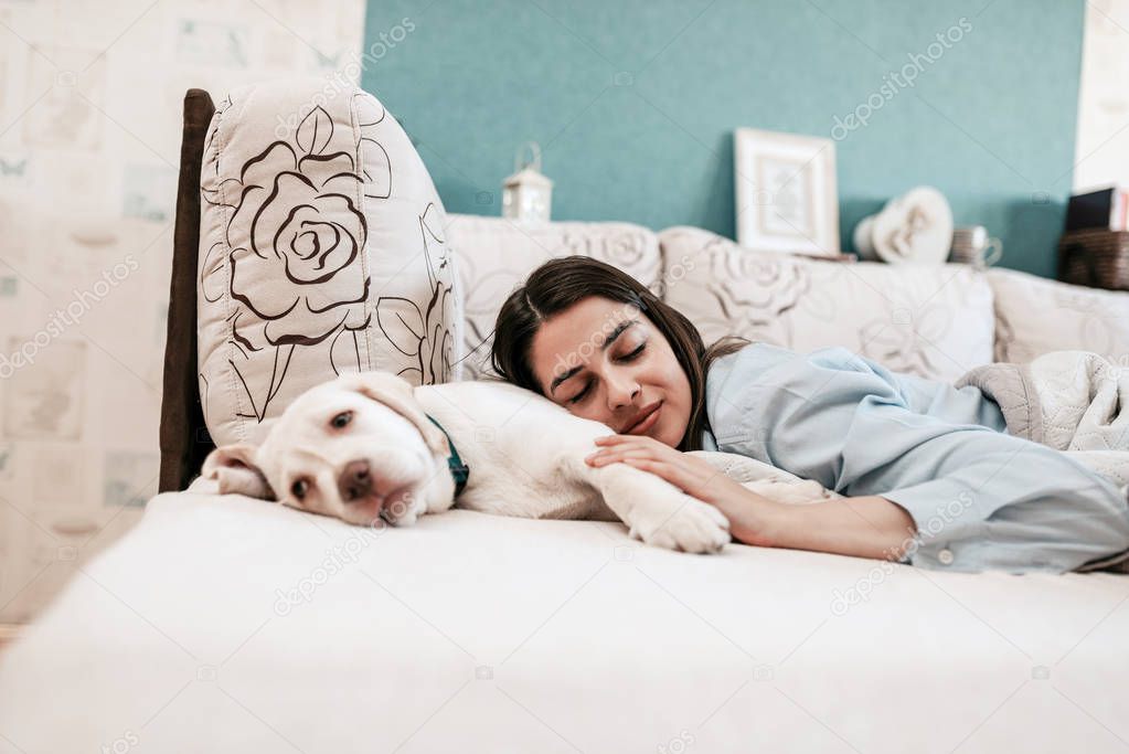 Woman sleeping with puppy on bed.