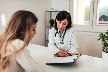Genç kadın hastasını tanı açıklayan doktor.