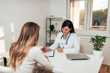 Güzel kadın doktor tıbbi ofis bir kadın hastada konuşuyor.