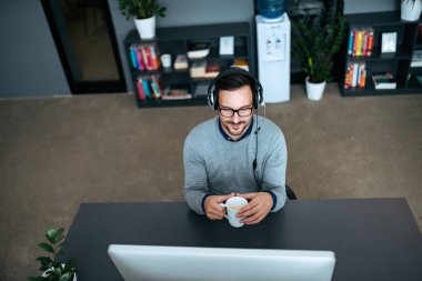 Teknoloji Yöneticisi bilgisayar monitörü seyir kulaklık ile yüksek açı görüntü.