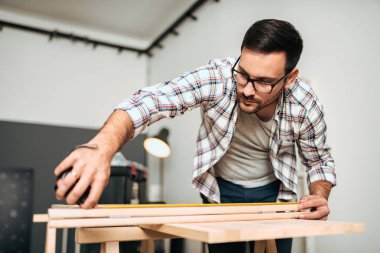Ölçüm bandı tutan genç şık ustası. DIY veya ev yenileme kavramı.