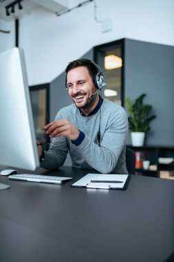 İş yerinizde modern ofis kulaklık ile rahat gülümseyen iş adamı. Kopya alanı.