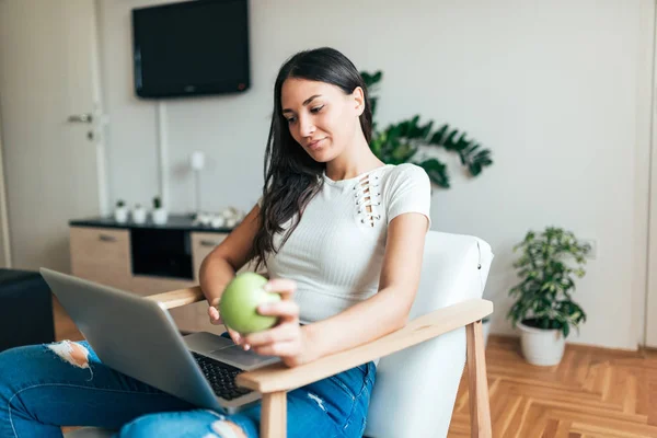 Jeune Femme Utilisant Ordinateur Portable Tenant Une Pomme Maison — Photo