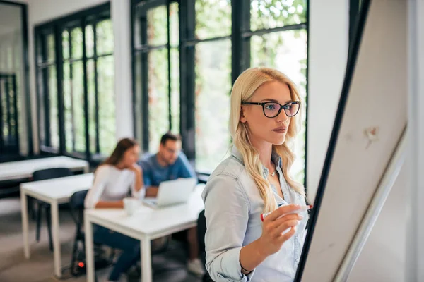 Ung Kvinna Skriver Blädderblocket Kollegor Bakgrunden — Stockfoto