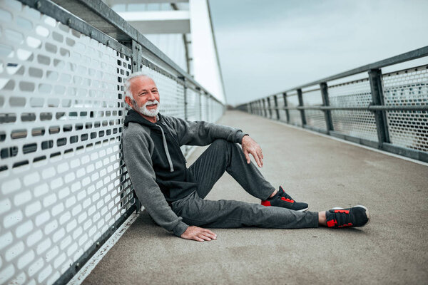 Senior athlete sitting on the city bridge.