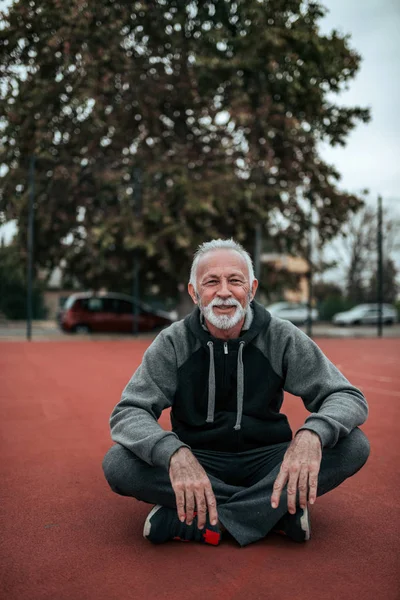 Portrait Senior Sportsman Sitting Tartan Track Looking Camera — Stock Photo, Image