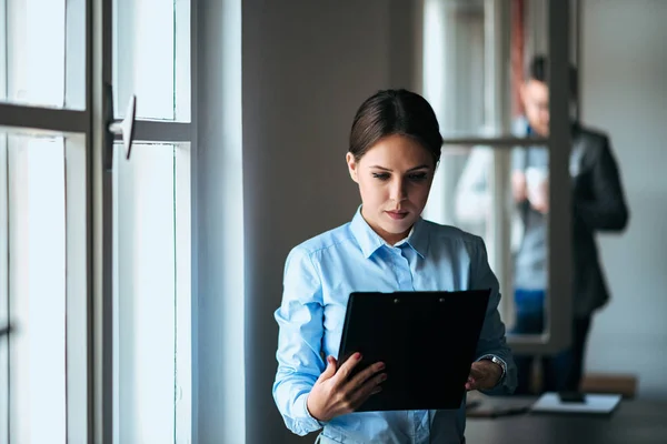 Young Businesswoman Examining Paper Documents While Standing Office Royalty Free Stock Images