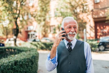 Cep telefonu açık havada üzerinde konuşuyor Modern üst düzey iş adamı.
