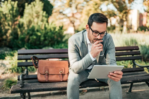 Açık havada tablet üzerinde çalışan genç işadamı.
