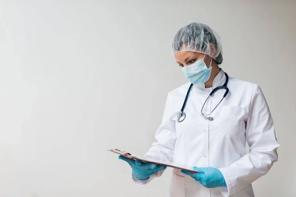 身穿无菌制服的女医生在康复室看剪贴板 — 图库照片