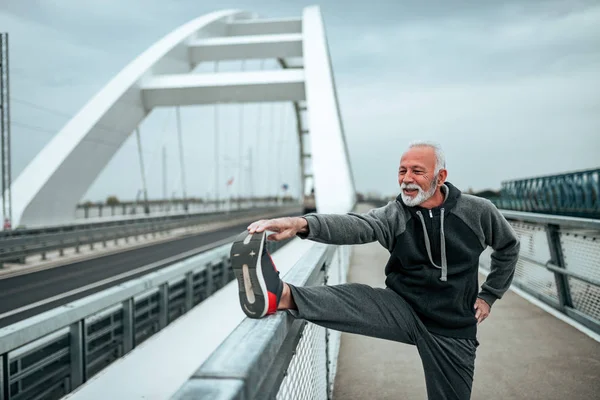 Sportivo Senior Che Estende All Aperto Sul Ponte Della Città — Foto Stock