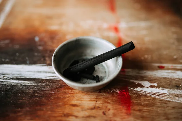 Drawing charcoal on a wooden palette.