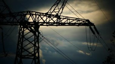 Bulutlu bir günbatımının arka planında yüksek voltaj direkleri. Enerjinin gücü. Güç hattı.