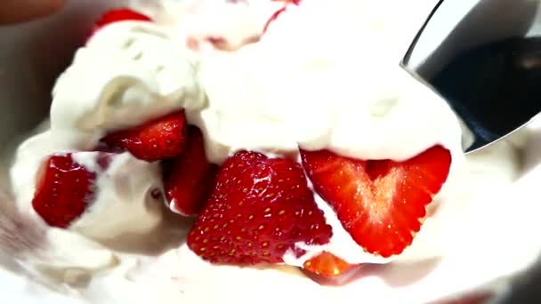 プレートにクリームが付いているイチゴ スプーンはサワークリームで美味しいデザートイチゴを食べます 夏の甘い赤いデザート — ストック動画