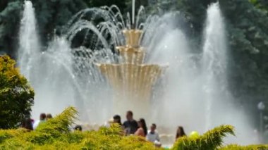 Şehir parkındaki çeşme. İnsanlar çeşmenin yanındaki parkta yürüyorlar..