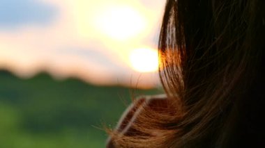 Güneşin ve bulutların veznedeki kıza bakar. Saç elle düzeltir.