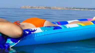 Bir kız deniz kenarındaki şişme bir yatakta dinleniyor ve yüzüyor. Tatildeki dalgalarda rahatla.. 