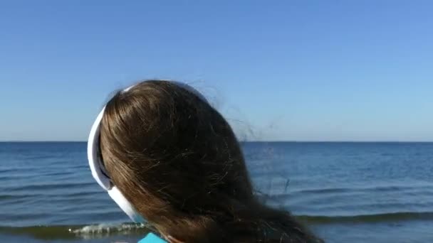 Ein Mädchen Strand Hört Musik Über Kopfhörer Zur Musik Entspannen — Stockvideo