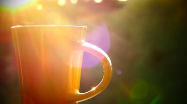 Doğada lezzetli çay. Bir fincan sıcak çay gün batımında. Siyah ya da yeşil çay buhar vardır. Elinde bir fincan bak.